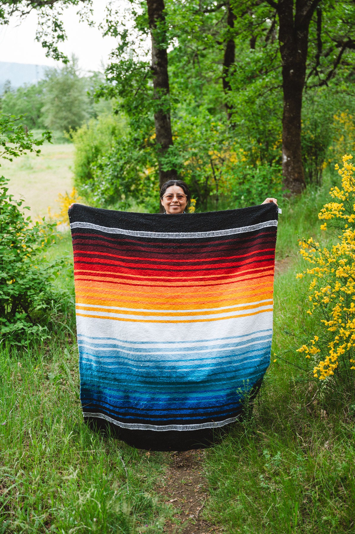 Woman holding handowoven mexican dog blanket in the forest