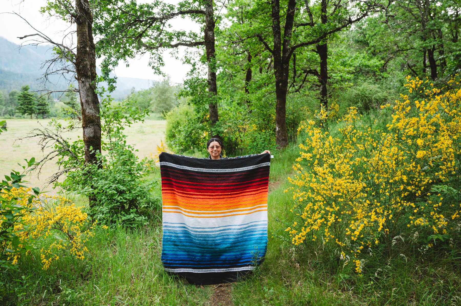 Woman holding handwoven mexican blanket in the forest
