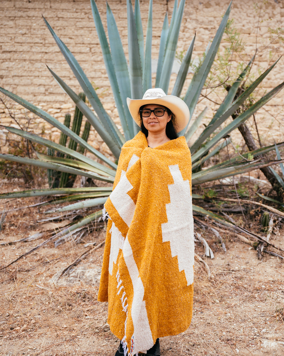 Girl wrapped in orange blanket in front of an agave in Oaxaca