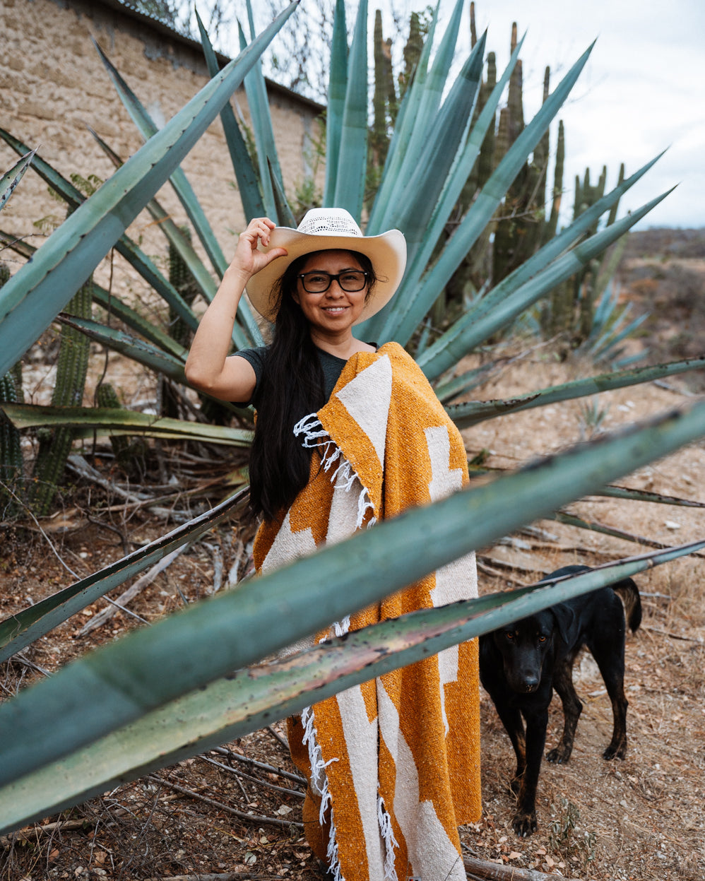 Girl wrapped in orange blanket in front of an agave in Oaxaca