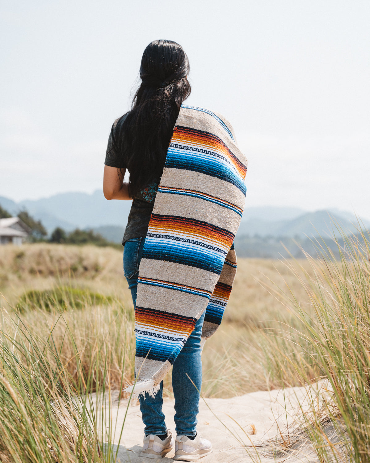 Girl wearing handwoven saltillo blanket in sand dunes