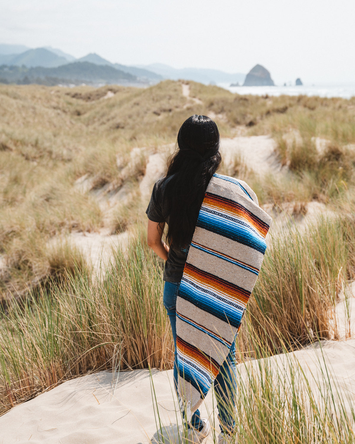 Girl wearing handwoven saltillo blanket in sand dunes