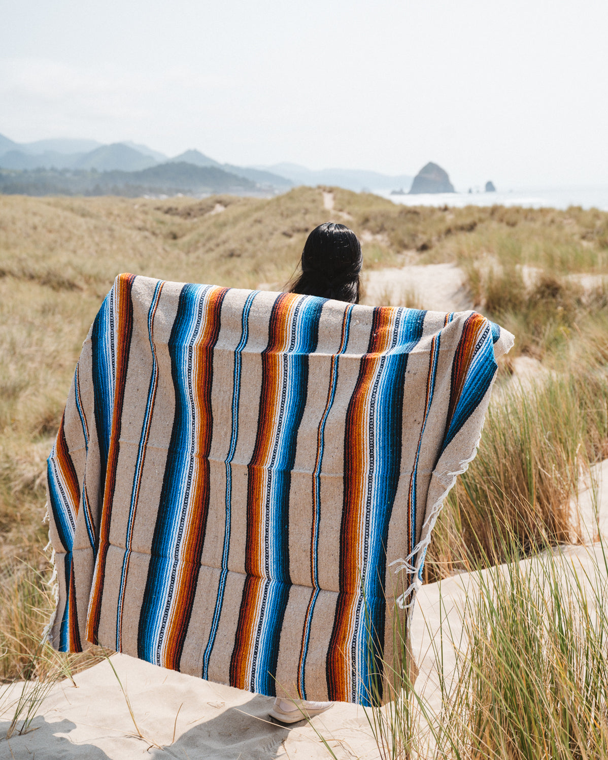 Girl wearing handwoven saltillo blanket in sand dunes