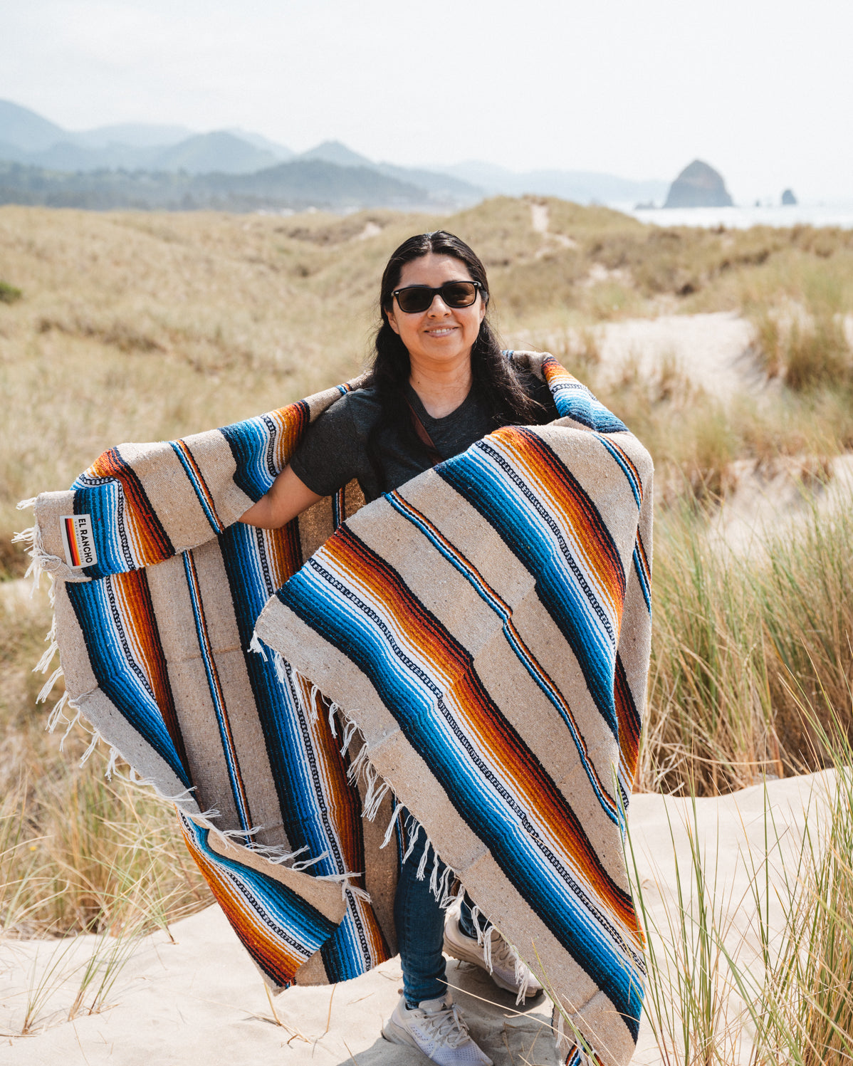 Girl wearing handwoven saltillo blanket in sand dunes