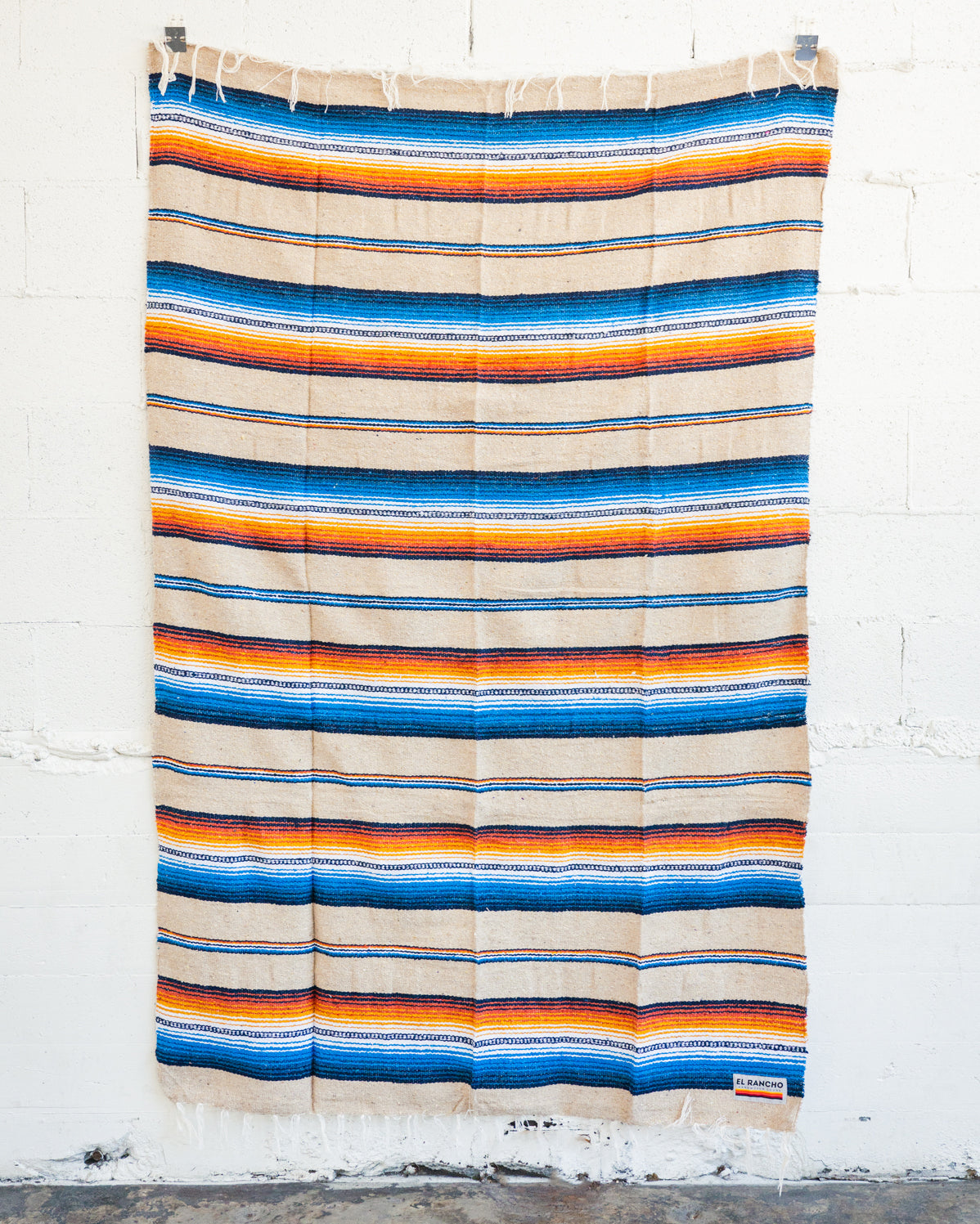 Saltillo blanket hanging from a white brick wall