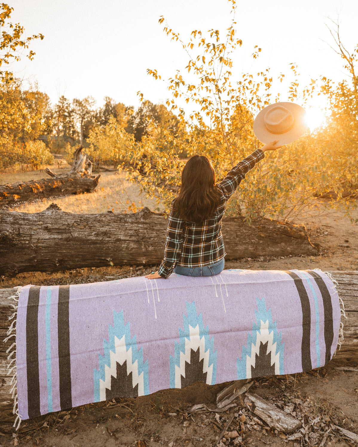 Girl sitting on lavender handwoven Mexican Blanket at sunset on the beach