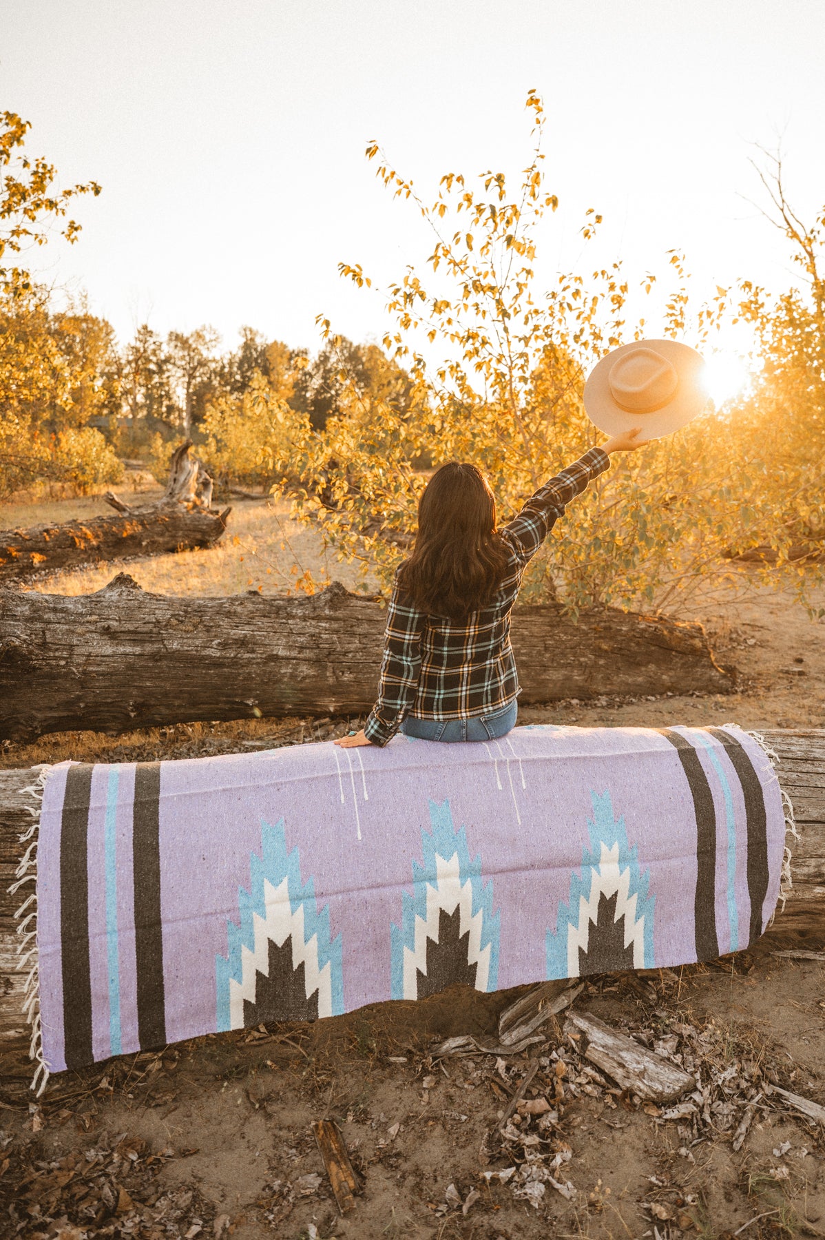 Girl sitting on lavender handwoven Mexican Blanket at sunset on the beach
