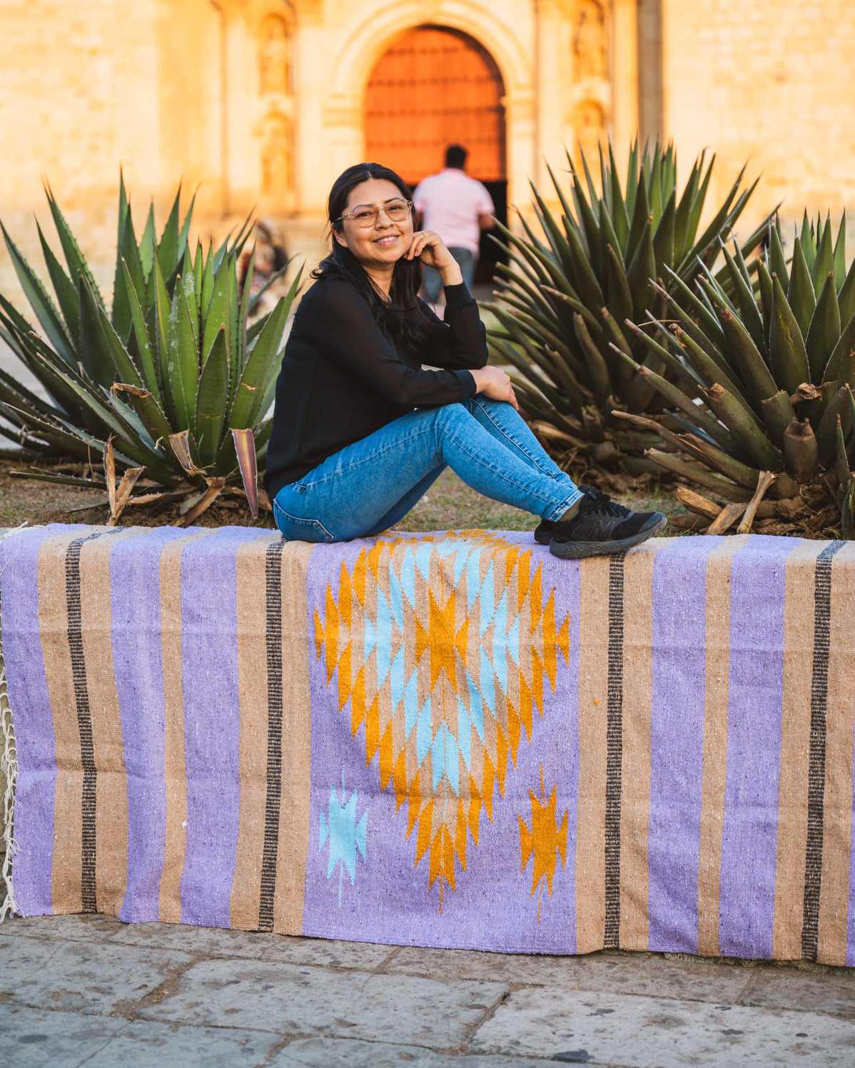 Santo Domingo Church Oaxaca and a girl sitting on a handwoven mexican blanket in front of it