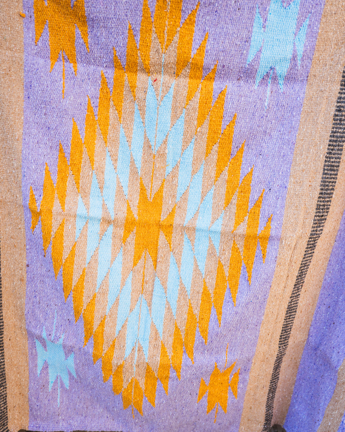 Textile with geometric pattern featuring orange and blue diamonds on a purple background