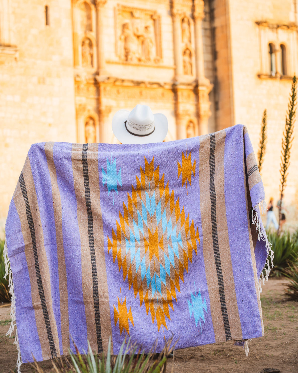 Santo Domingo Church Oaxaca and a girl standing with a handwoven mexican blanket in front of it