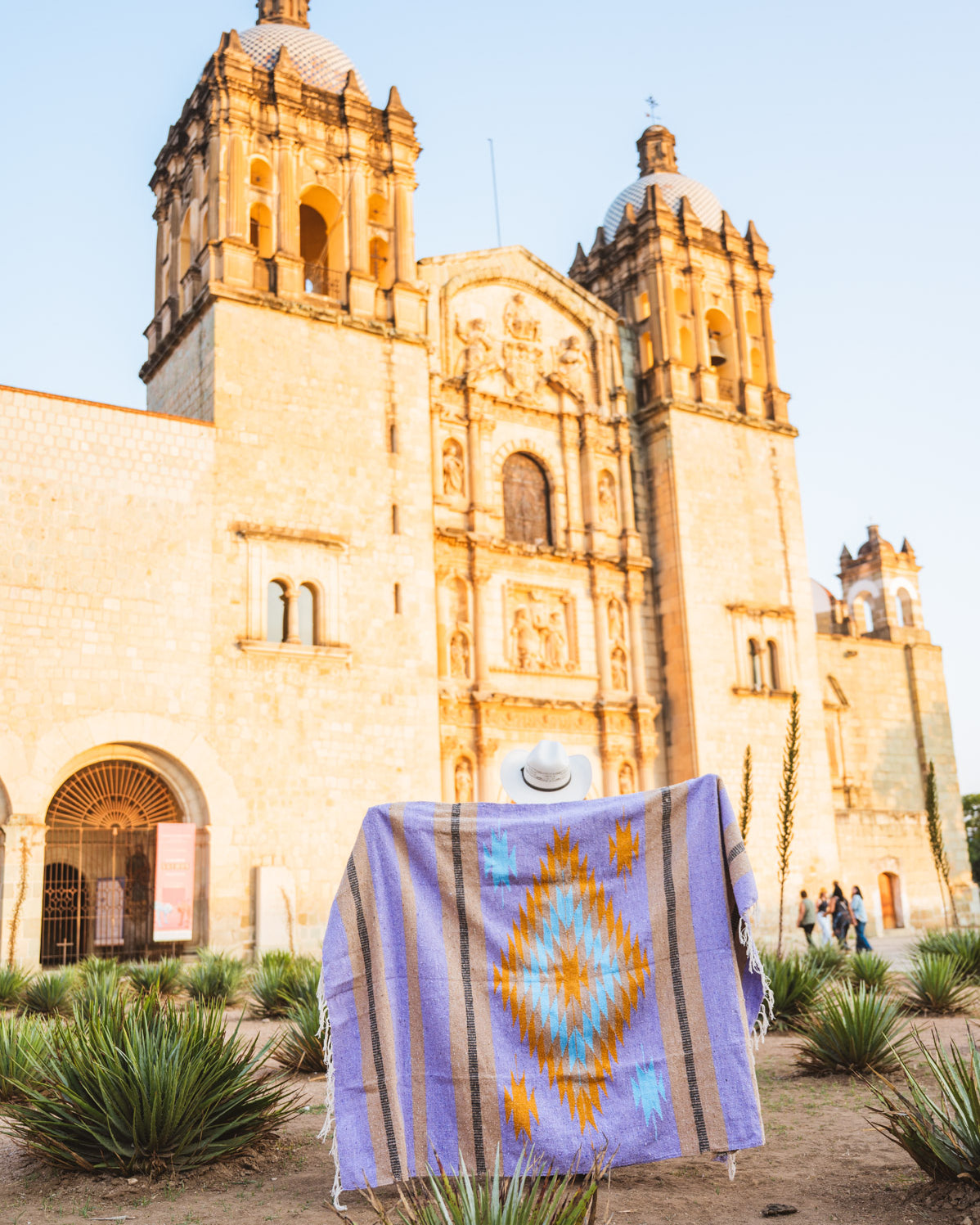 Santo Domingo Church Oaxaca and a girl standing with a handwoven mexican blanket in front of it