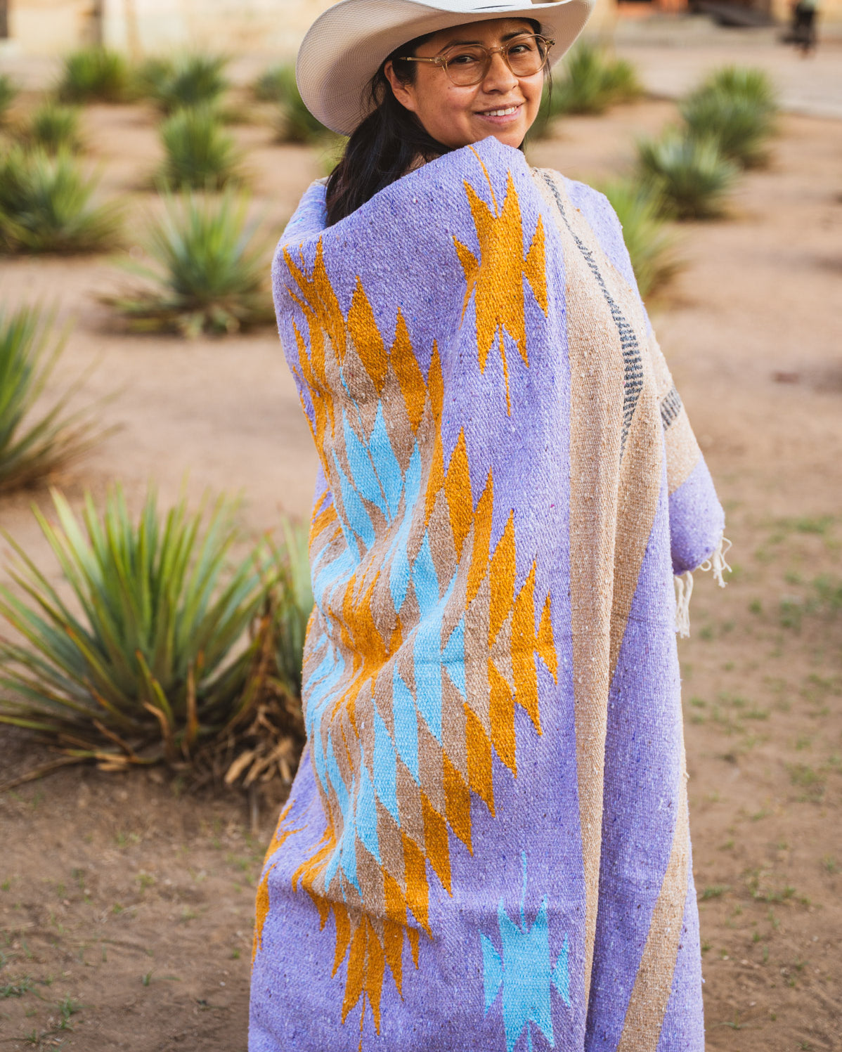 Santo Domingo Church Oaxaca and a girl standing with a handwoven mexican blanket in front of it