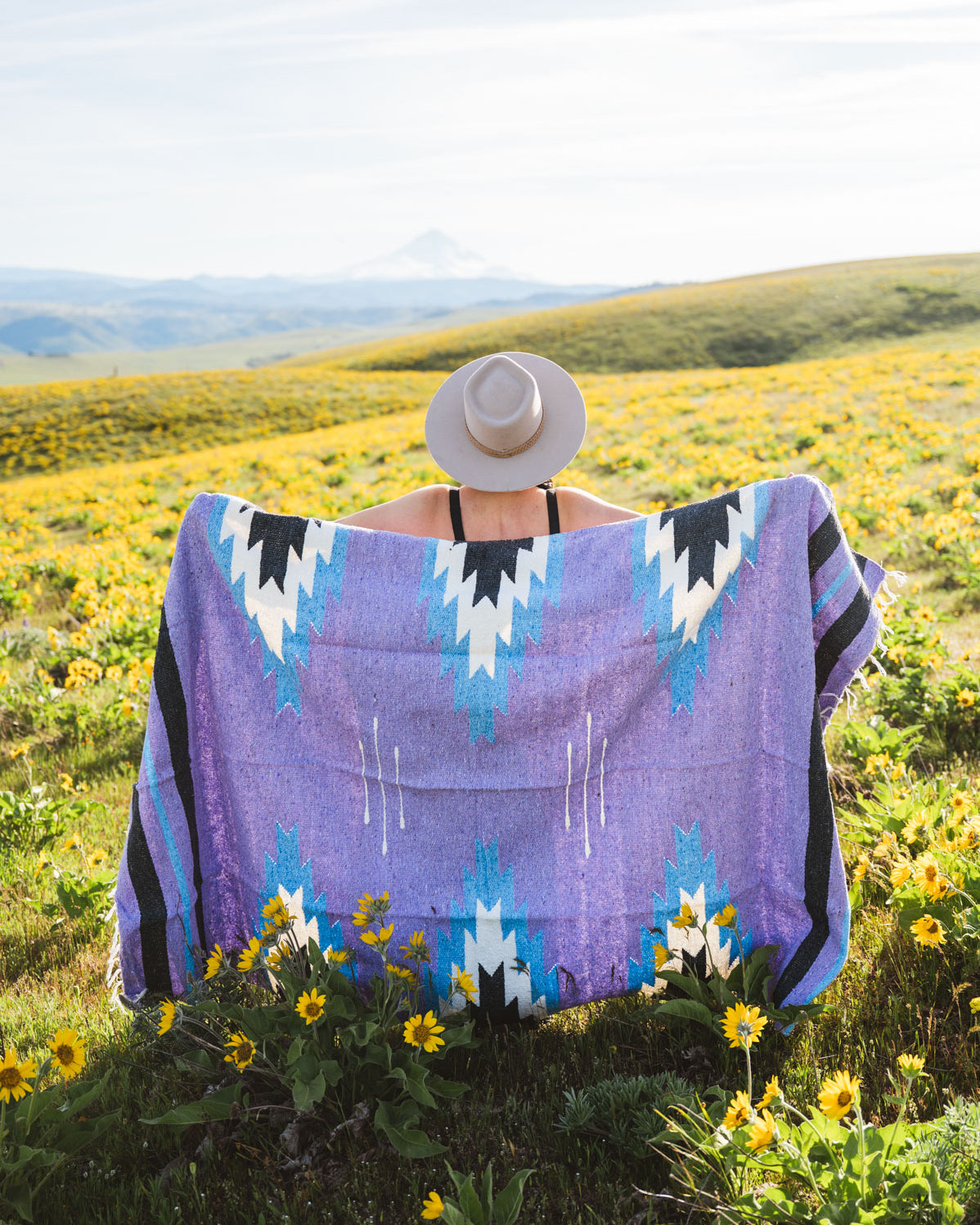 Person wearing a purple patterned towel in a field with wildflowers
