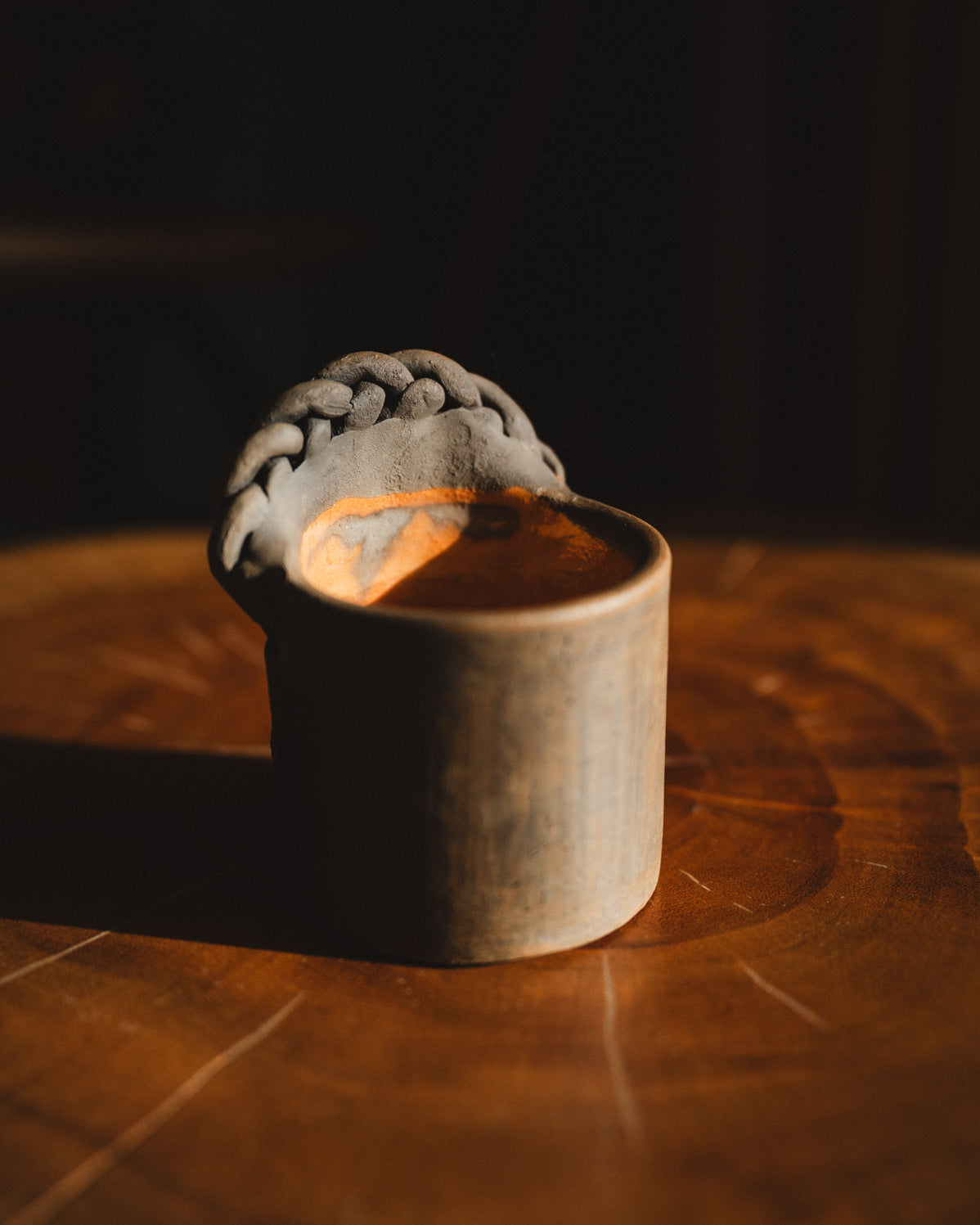Small wooden cup with a gray woven object on a dark background