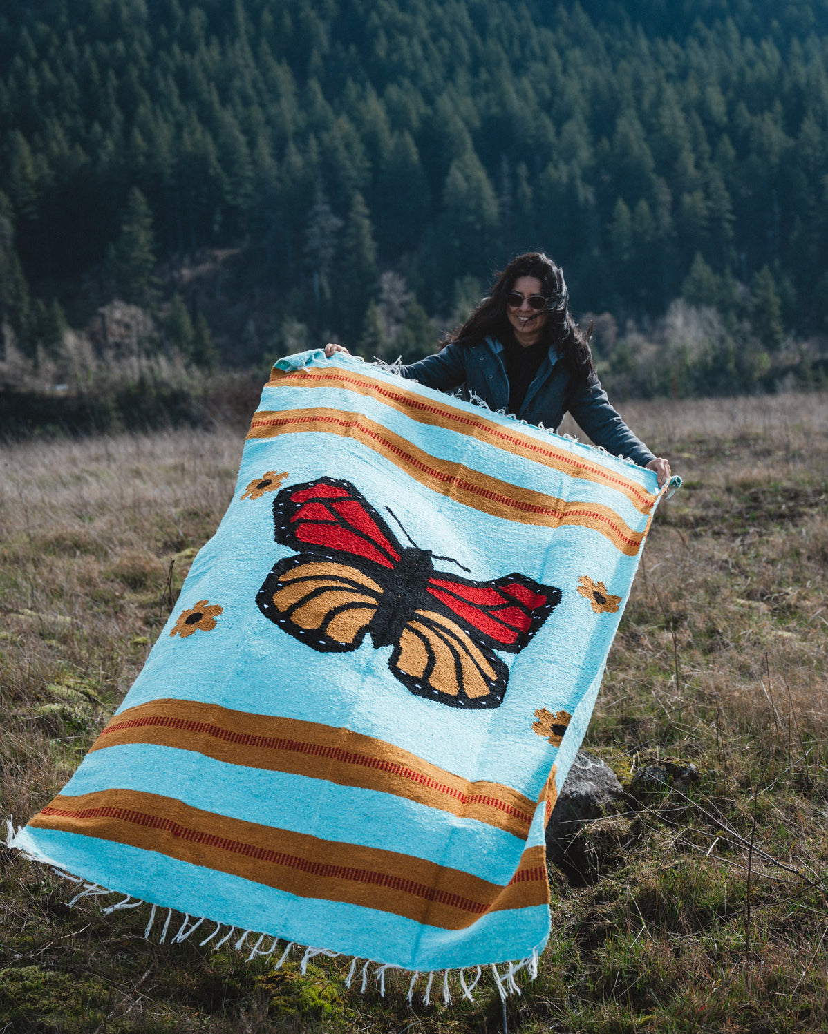Woman holding monarch butterfly blanket in a field
