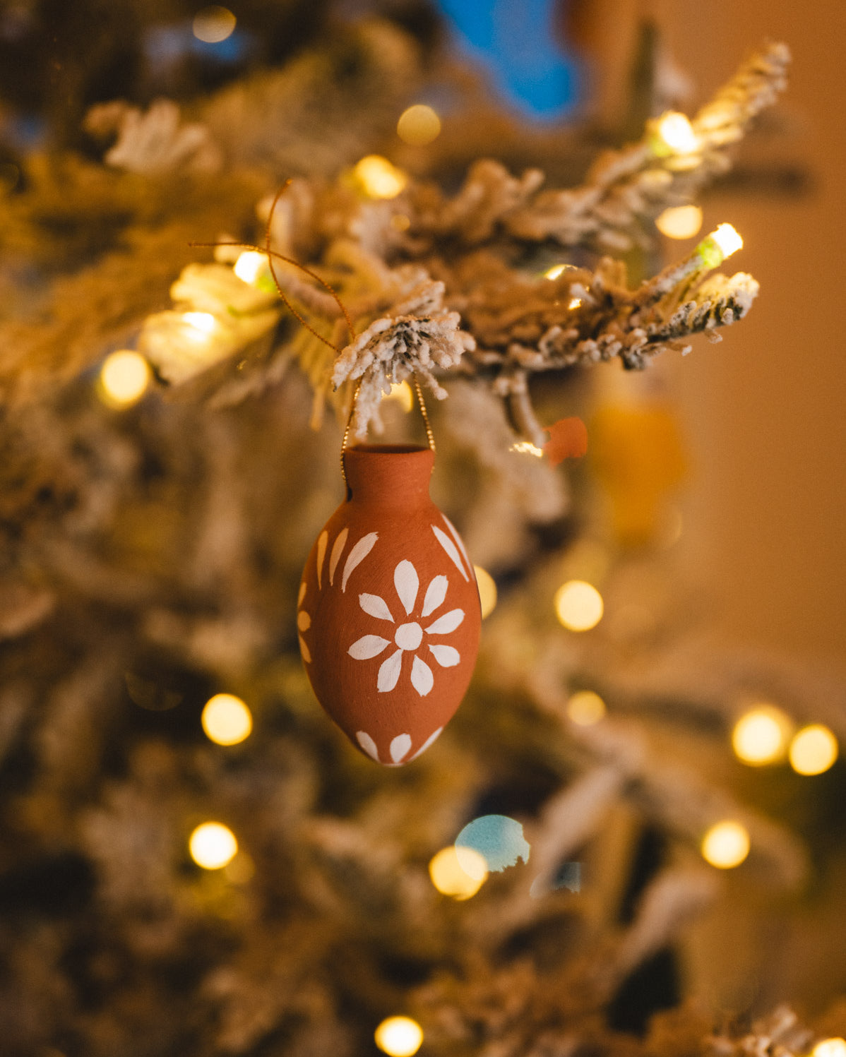 Decorative egg ornament on a Christmas tree with lights in the background
