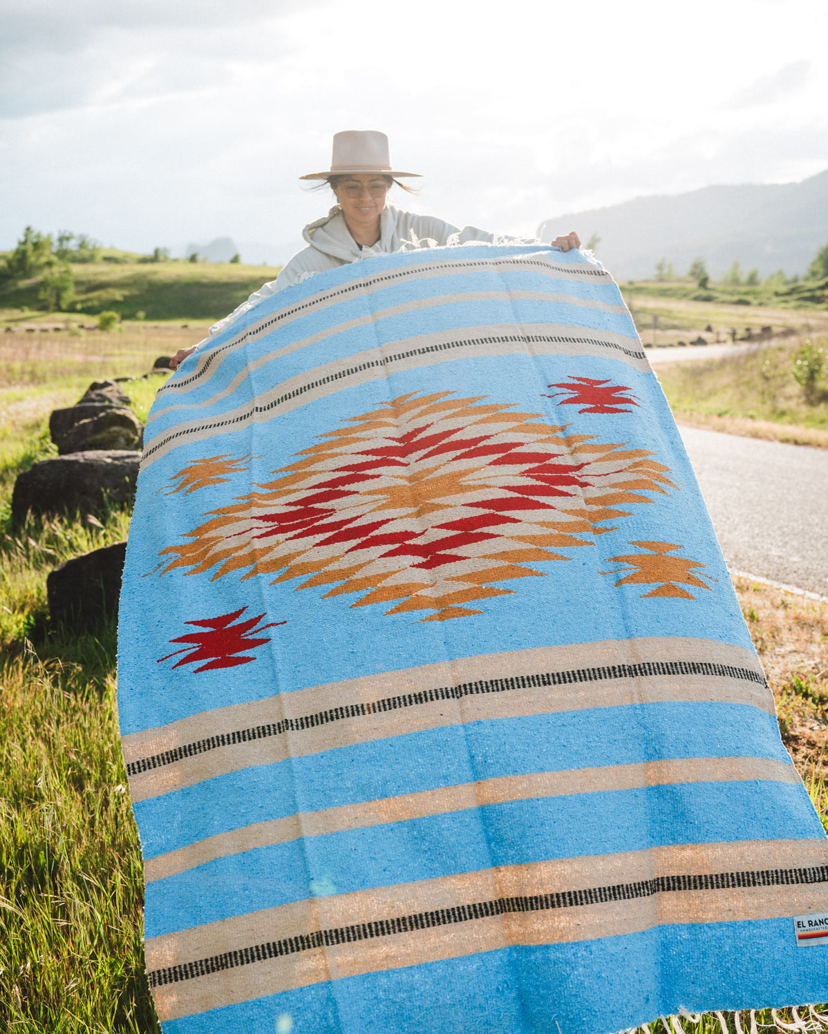Mexican woman holding a blue handwoven mexican blanket