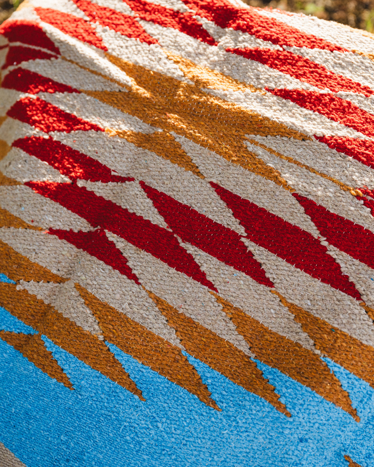Blue and red mexican diamond blanket laying on the ground