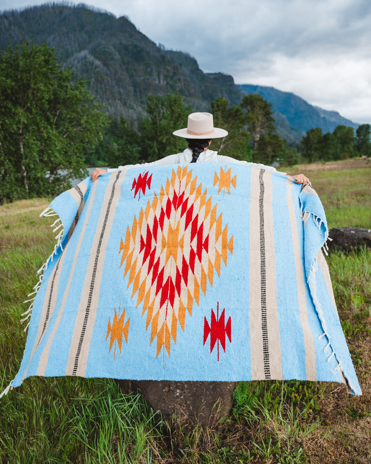 Mexican woman holding a blue handwoven mexican blanket