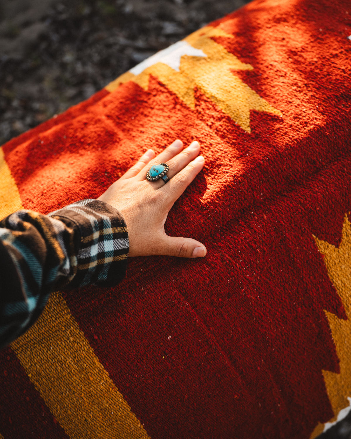 Hand with a ring on a colorful woven surface