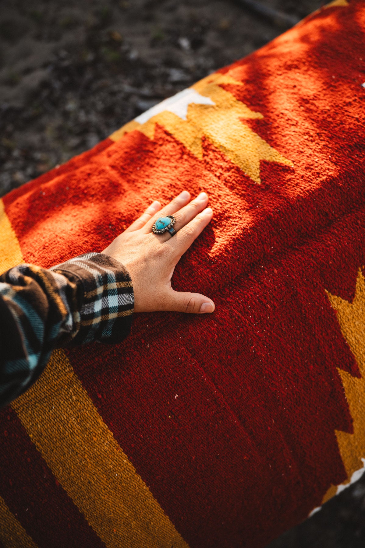 Hand with a ring on a colorful woven surface