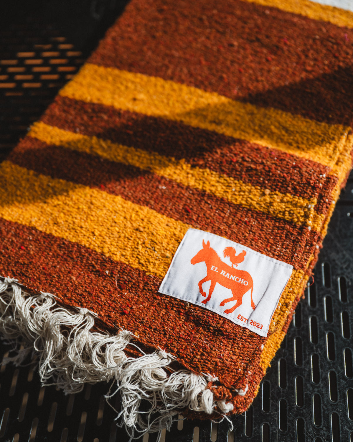 Striped fabric with fringes and a brand label on a textured surface