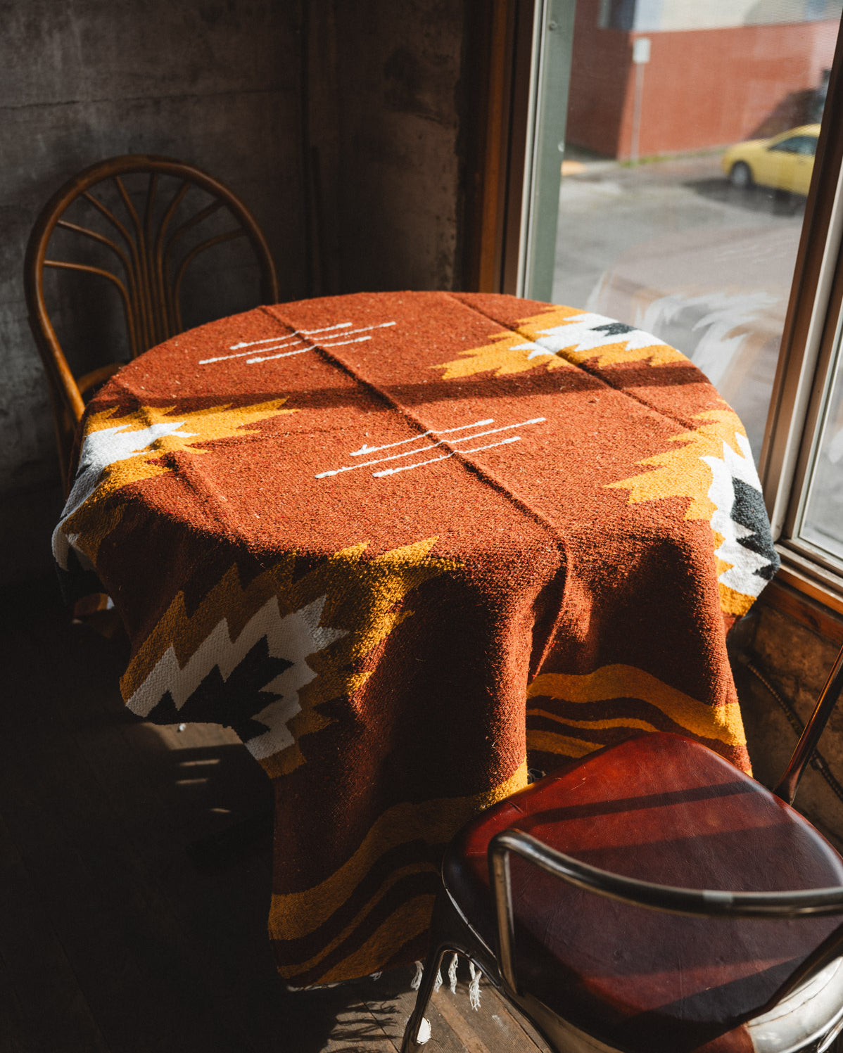 Table with a patterned tablecloth in a window-lined room