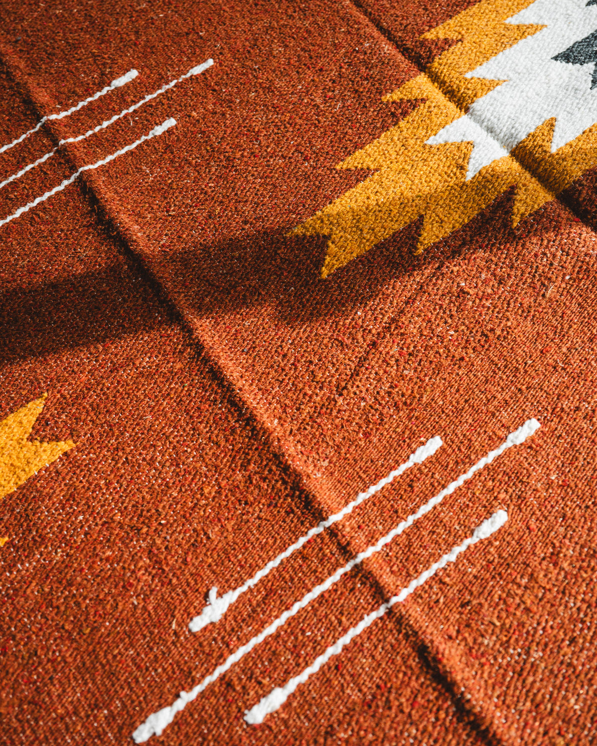 Close-up of a textured brown fabric with white lines and yellow accents