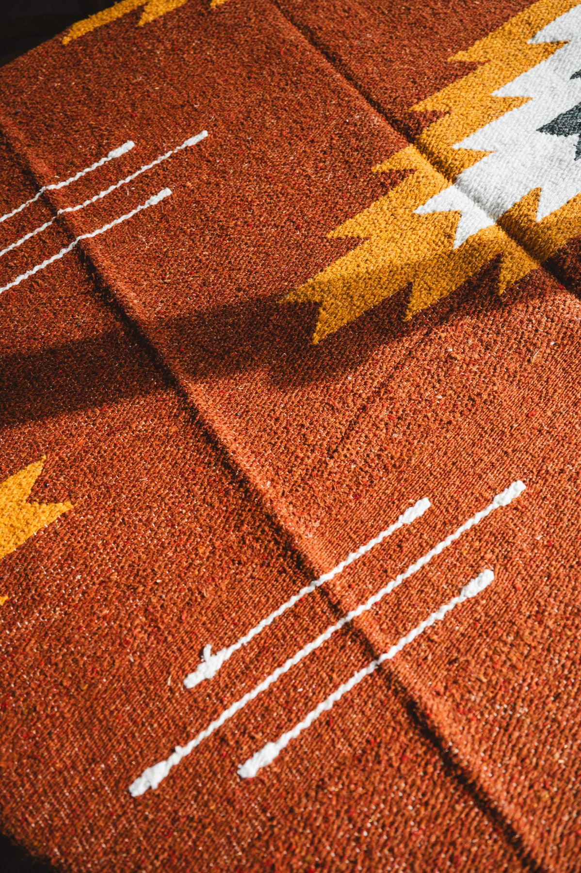 Close-up of a textured brown fabric with white lines and yellow accents