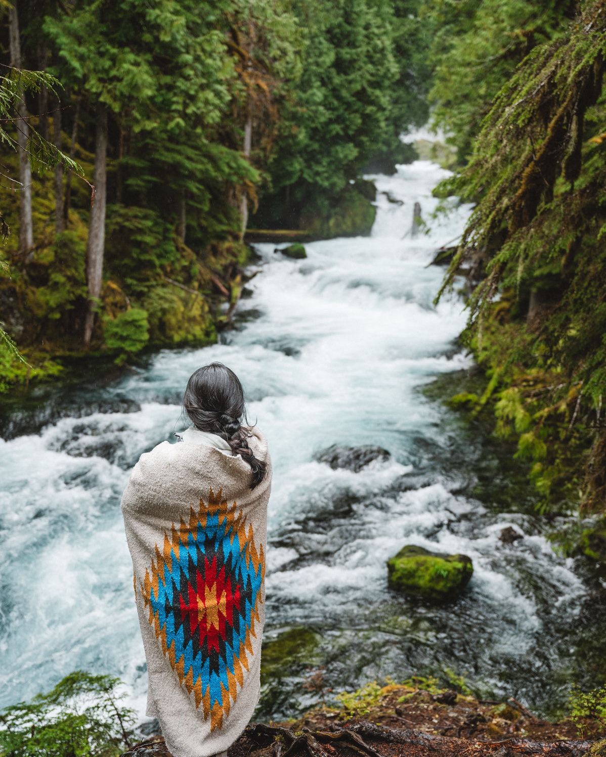 Woman wearing a Handwoven Mexican Blanket in front of Sahalie Falls Oregon in the Mckenzie River Corridor