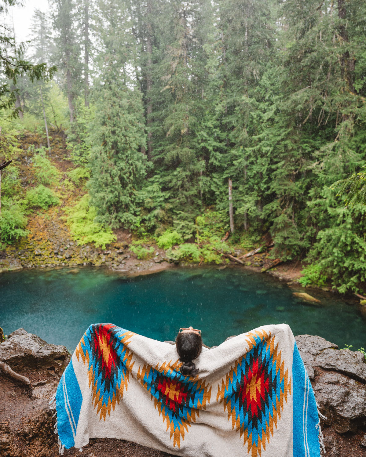 Woman wearing a Handwoven Mexican Blanket in front of Blue Pool, Oregon in the Mckenzie River Corridor