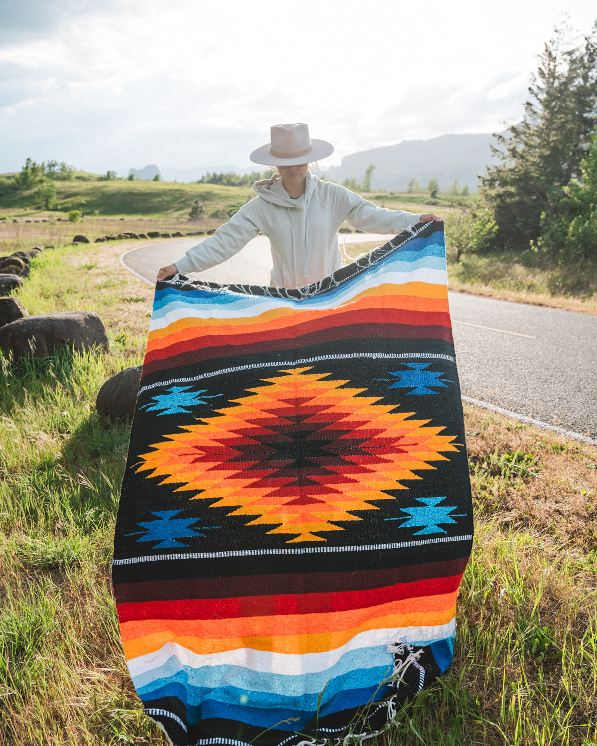 Mexican woman holding a multicolored handwoven mexican blanket with diamond saltillo design
