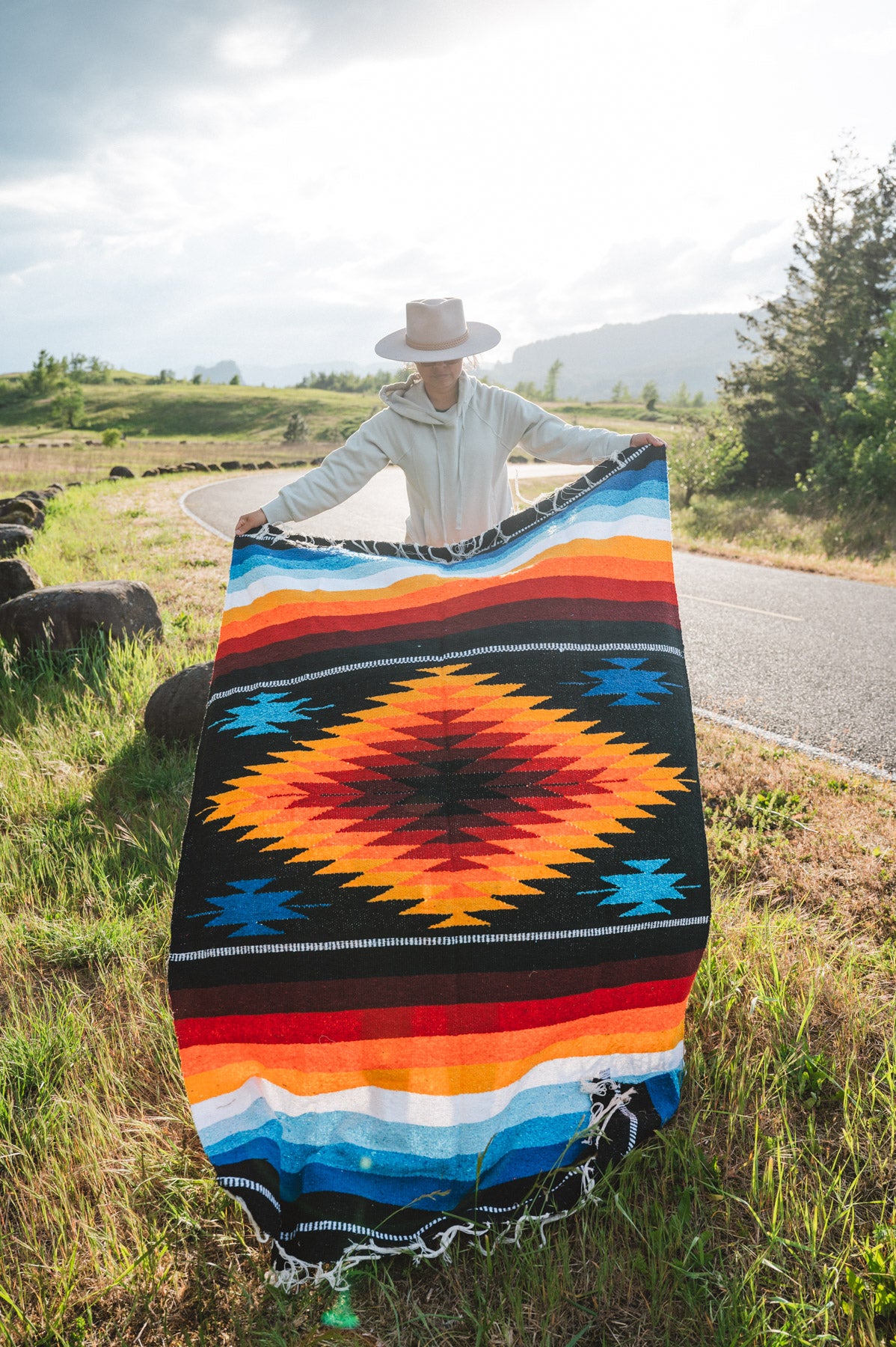 Mexican woman holding a multicolored handwoven mexican blanket with diamond saltillo design