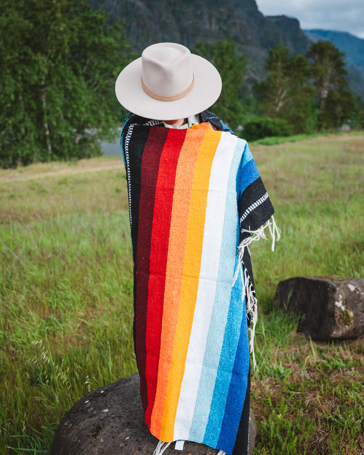 Mexican woman wrapped in a multicolored handwoven mexican blanket with diamond saltillo design