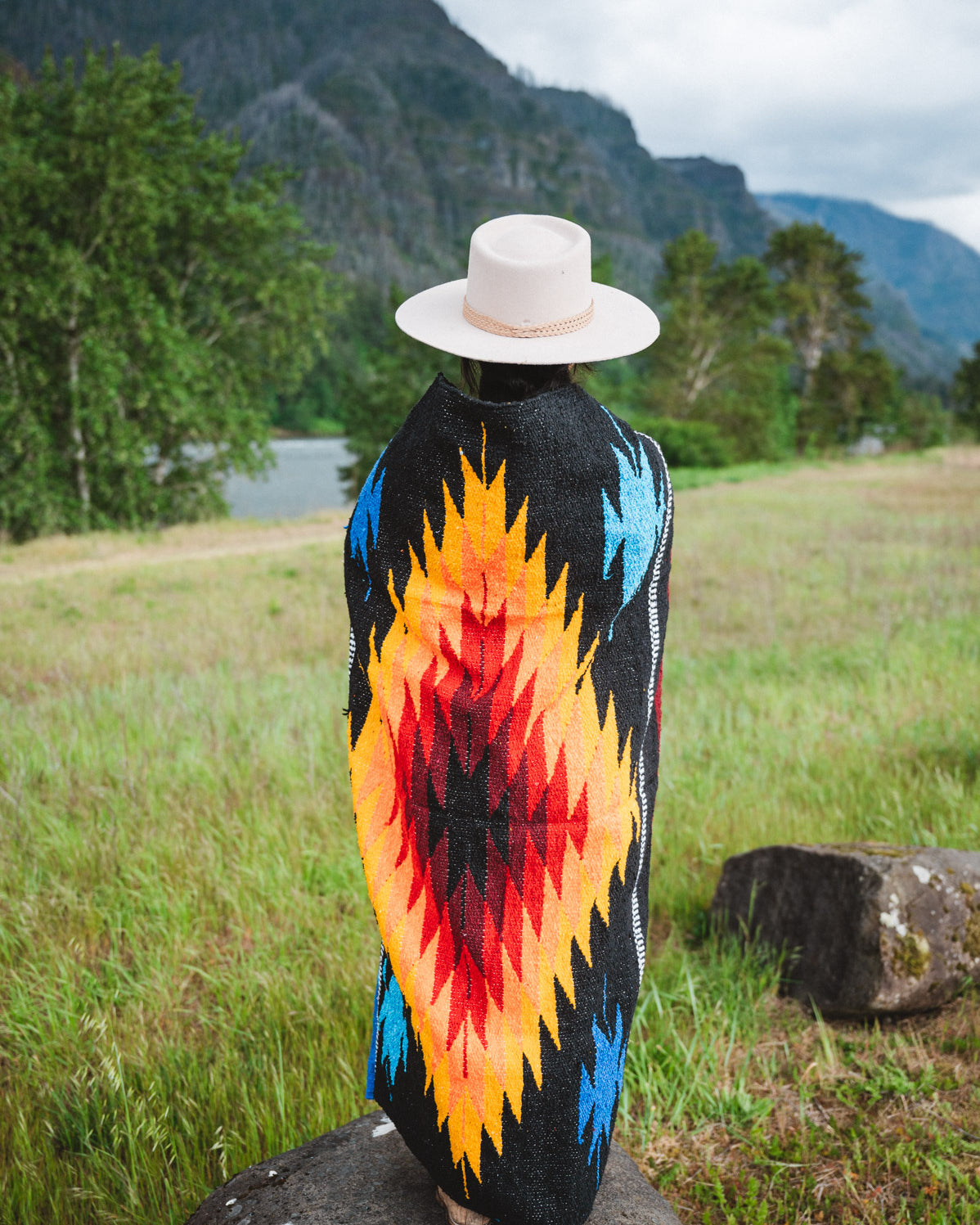 Mexican woman wrapped in a multicolored handwoven mexican blanket with diamond saltillo design