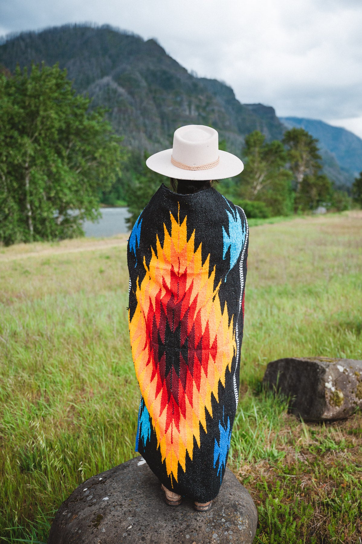 Mexican woman wrapped in a multicolored handwoven mexican blanket with diamond saltillo design