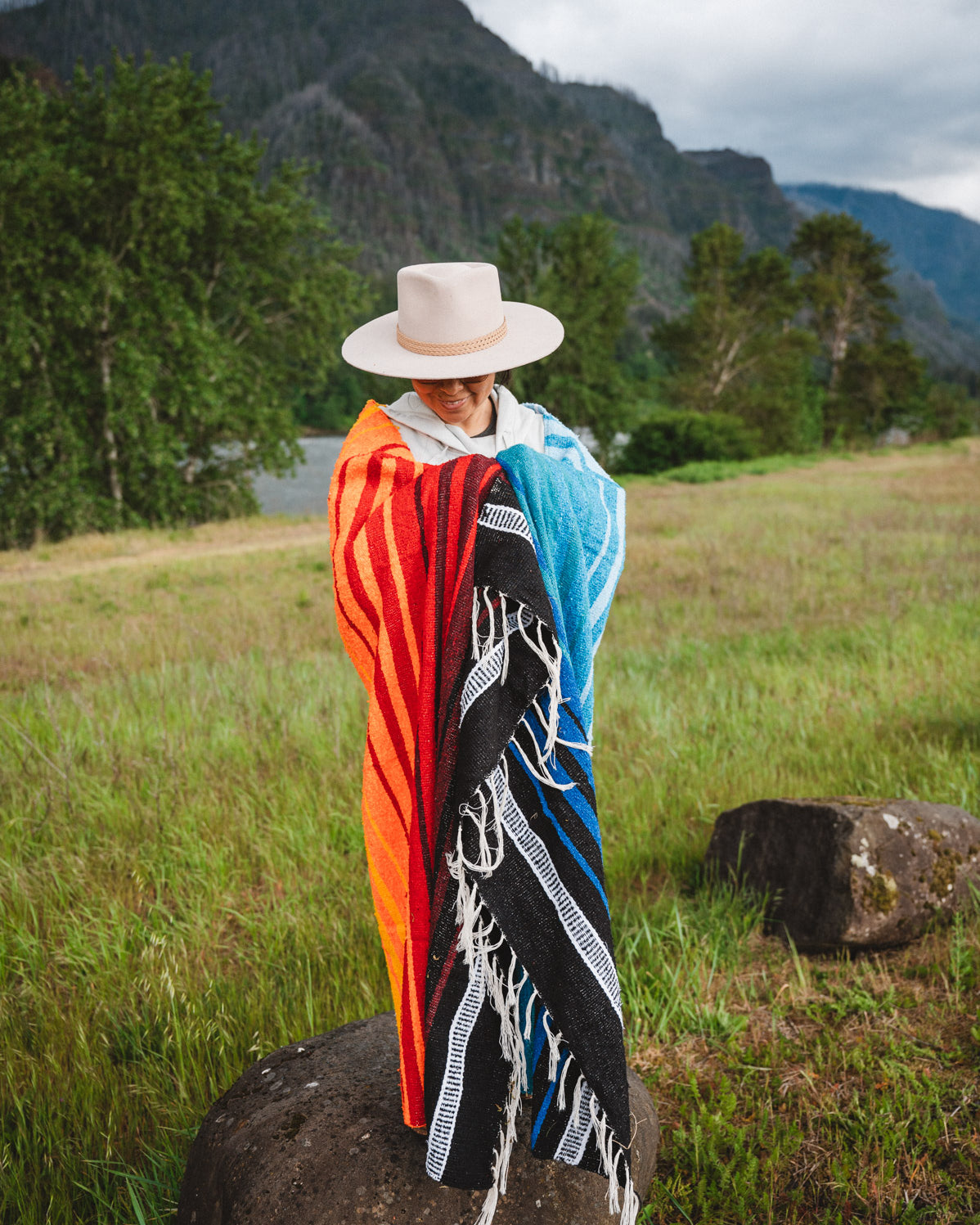 Mexican woman wrapped in a multicolored handwoven mexican blanket with diamond saltillo design