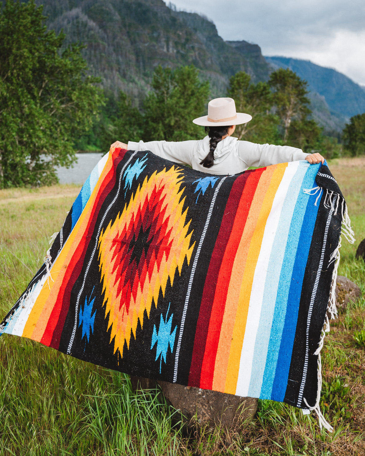 Mexican woman wrapped in a multicolored handwoven mexican blanket with diamond saltillo design