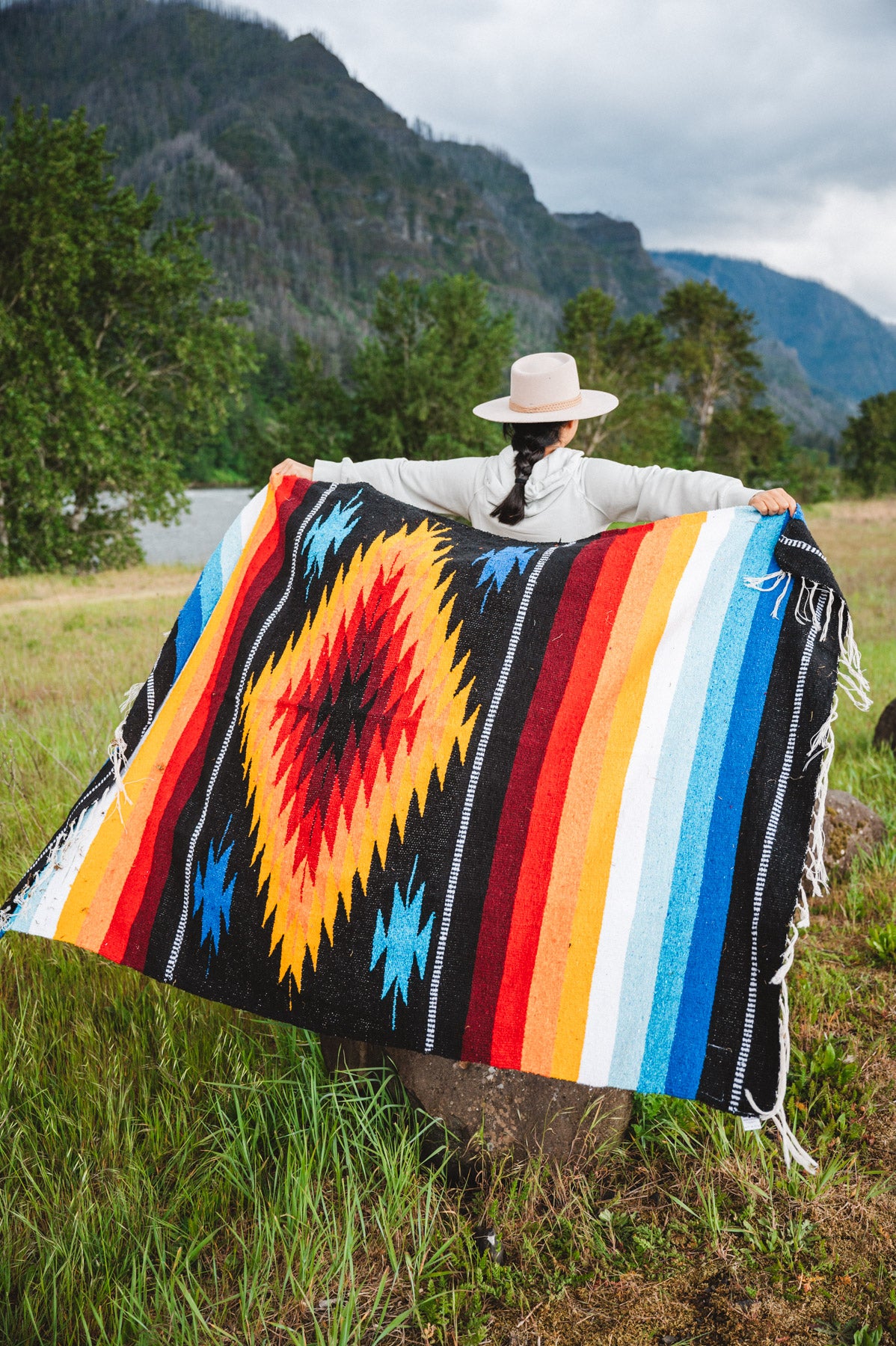 Mexican woman wrapped in a multicolored handwoven mexican blanket with diamond saltillo design