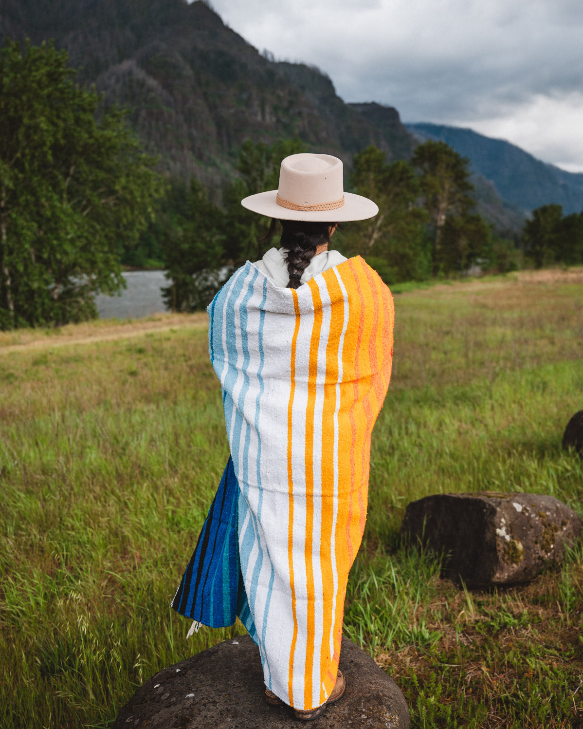 Mexican woman wrapped in a multicolored handwoven mexican blanket with striped saltillo design