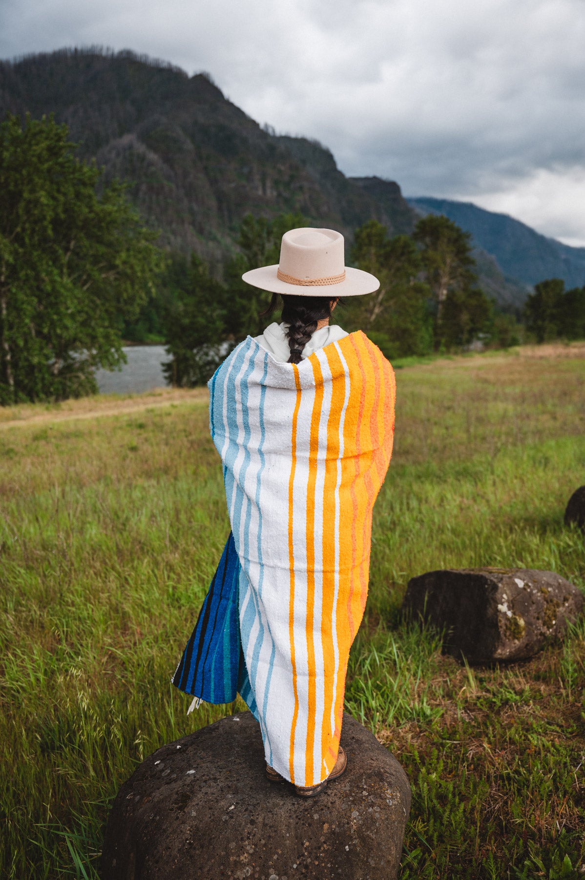 Mexican woman wrapped in a multicolored handwoven mexican blanket with striped saltillo design
