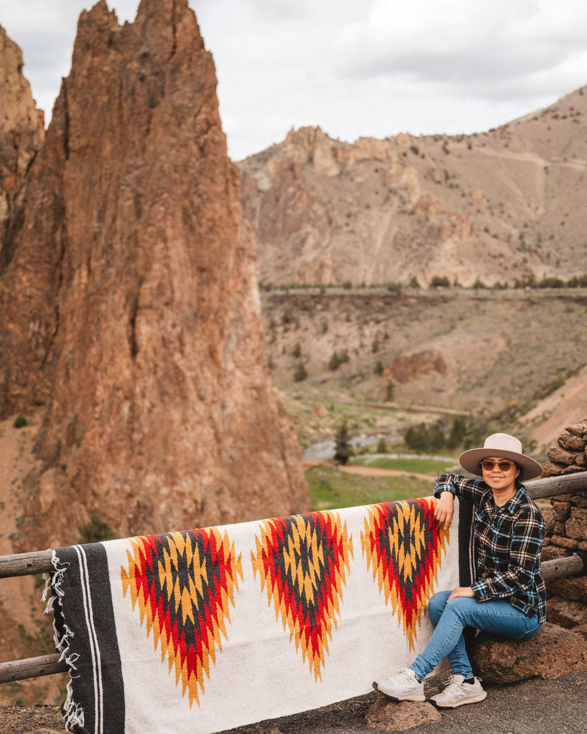 Woman sitting next to southwest diamond handwoven blanket at smith rock state park oregon