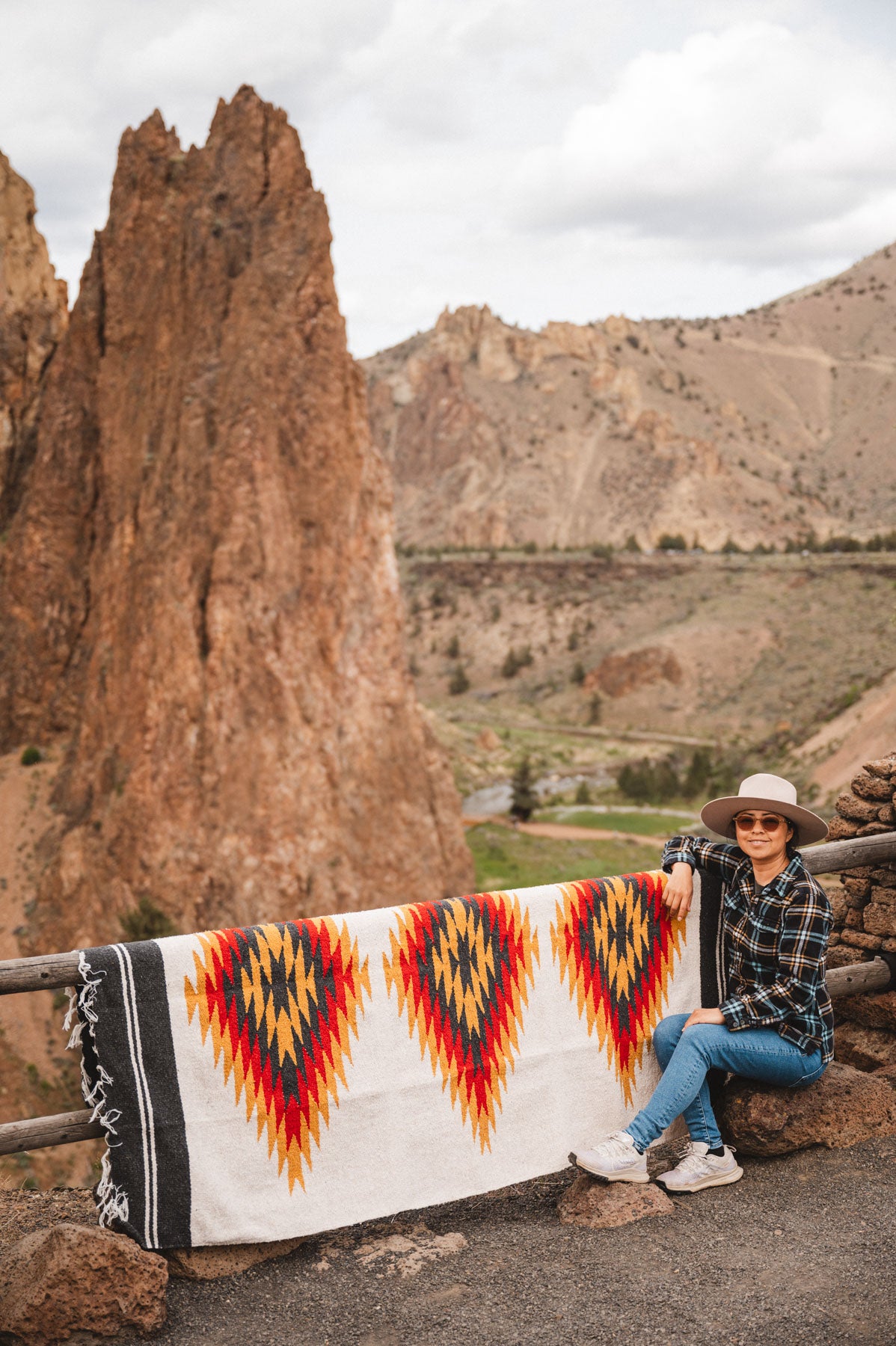 Woman sitting next to southwest diamond handwoven blanket at smith rock state park oregon