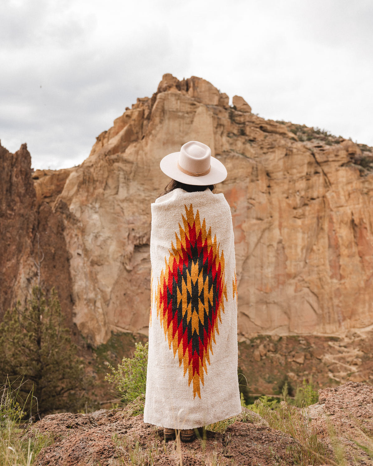Woman wearing a southwest diamond handwoven blanket at smith rock state park oregon