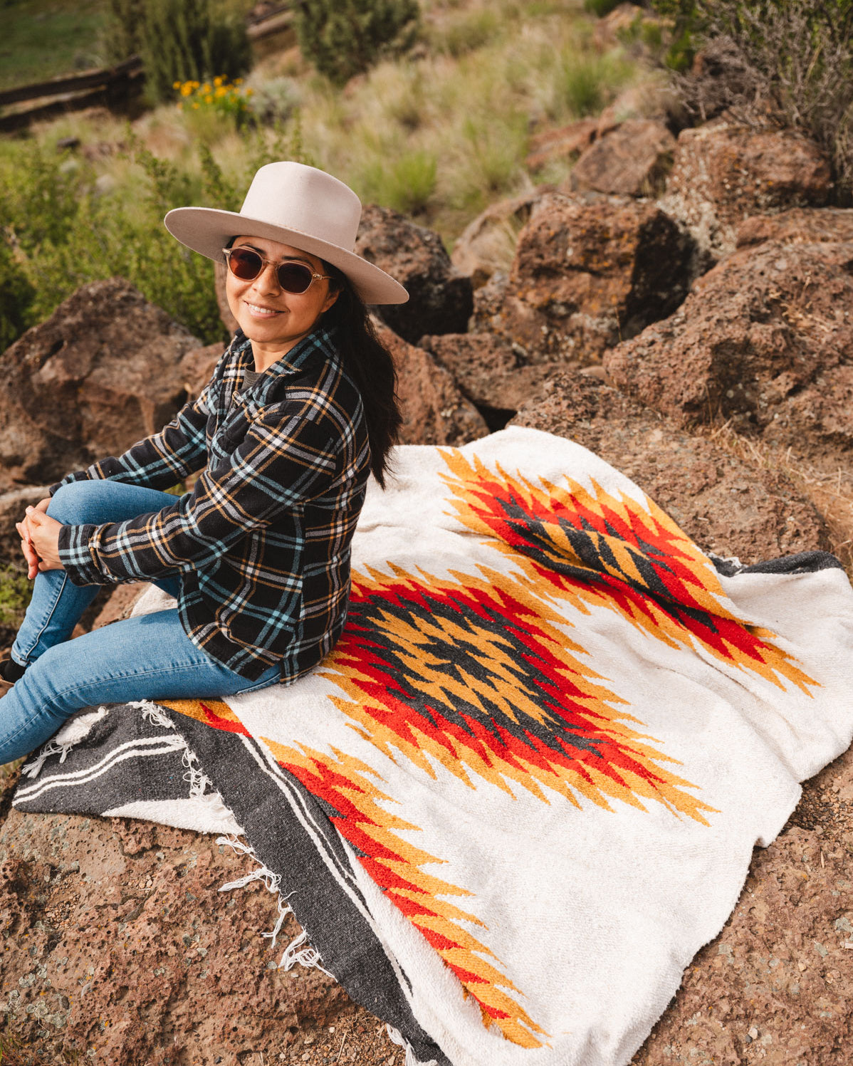 Woman sitting on a southwest diamond handwoven blanket at smith rock state park oregon