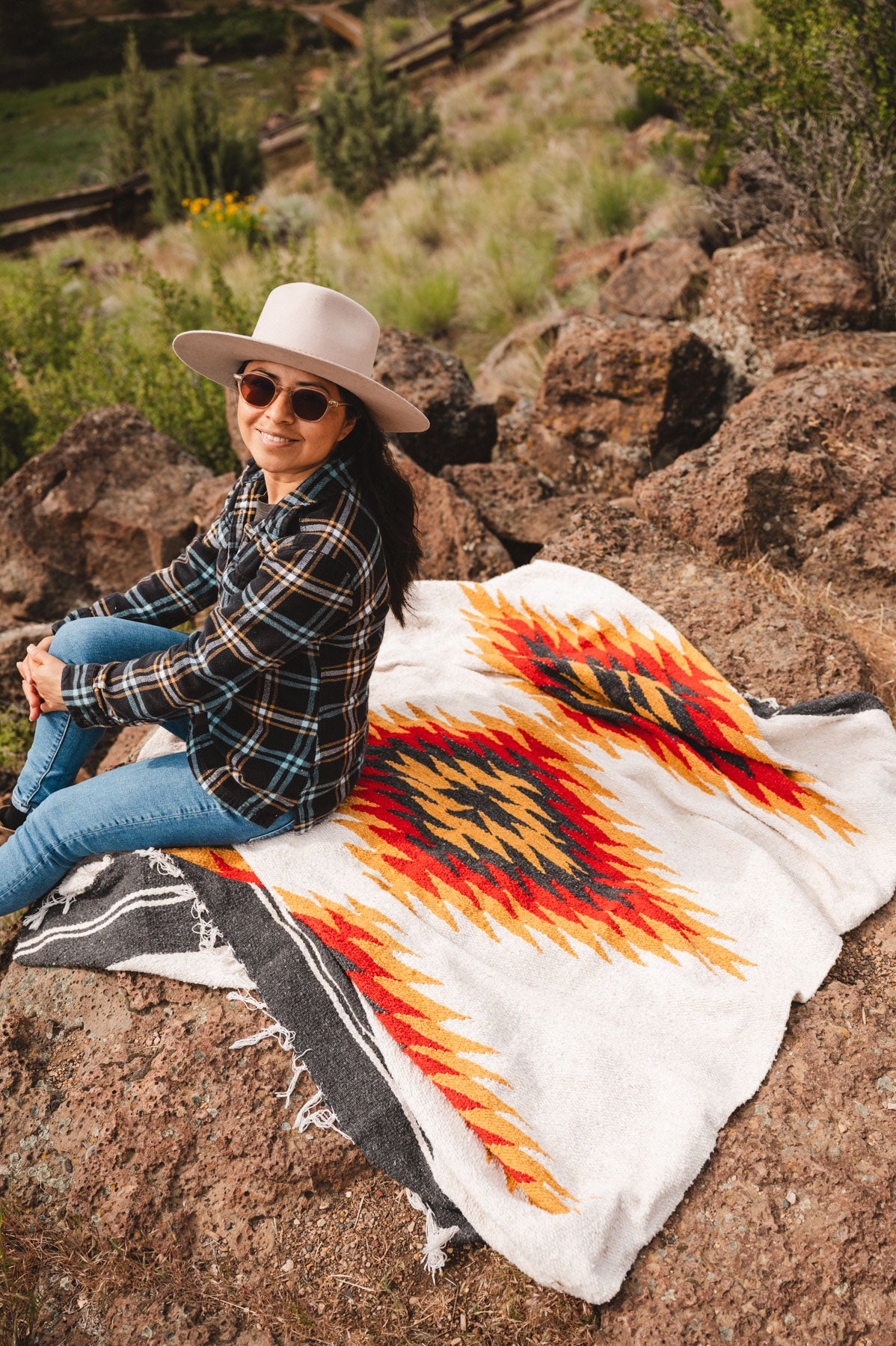Woman sitting on a southwest diamond handwoven blanket at smith rock state park oregon