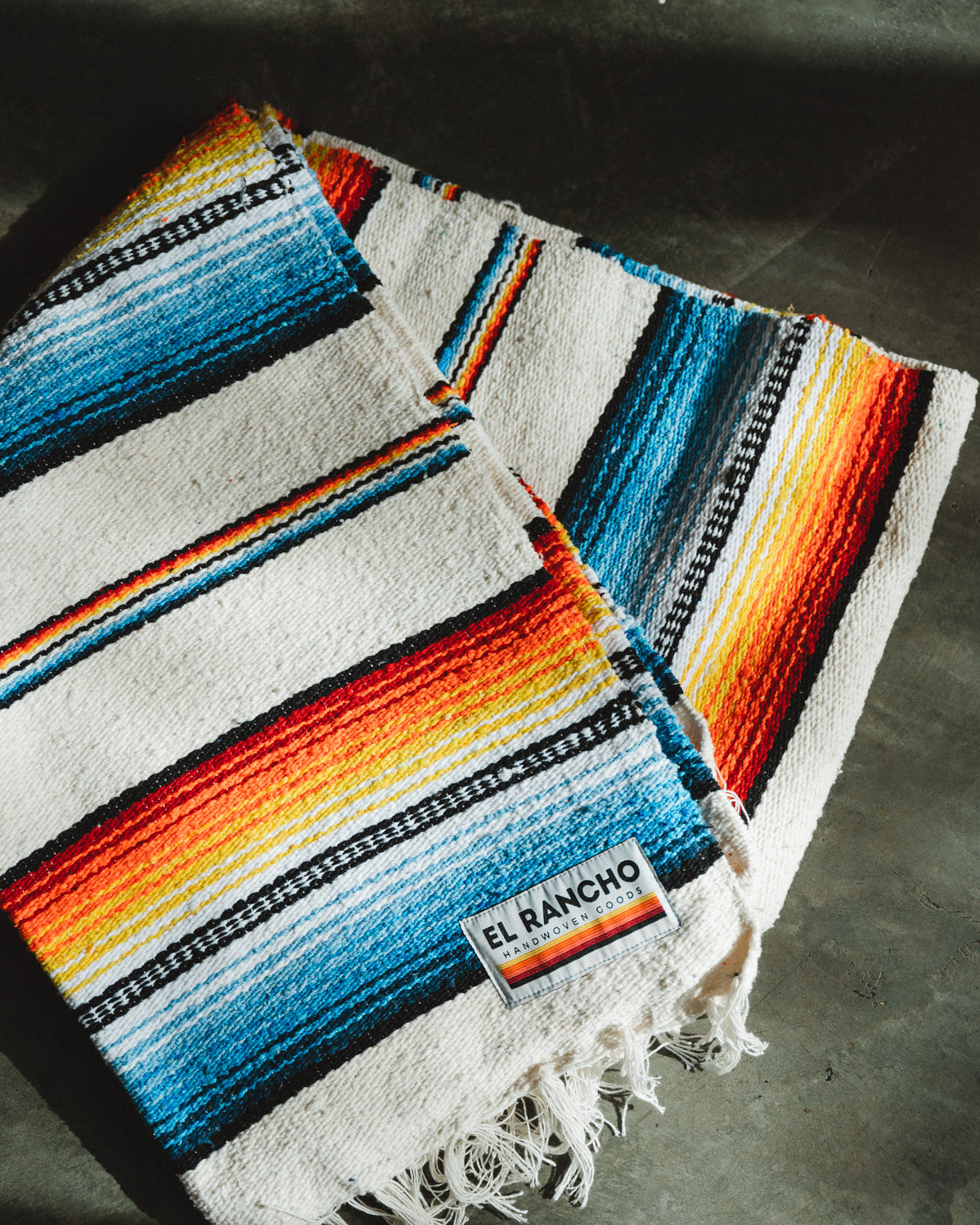 Handwoven socal retro colored saltillo blanket folded on ground