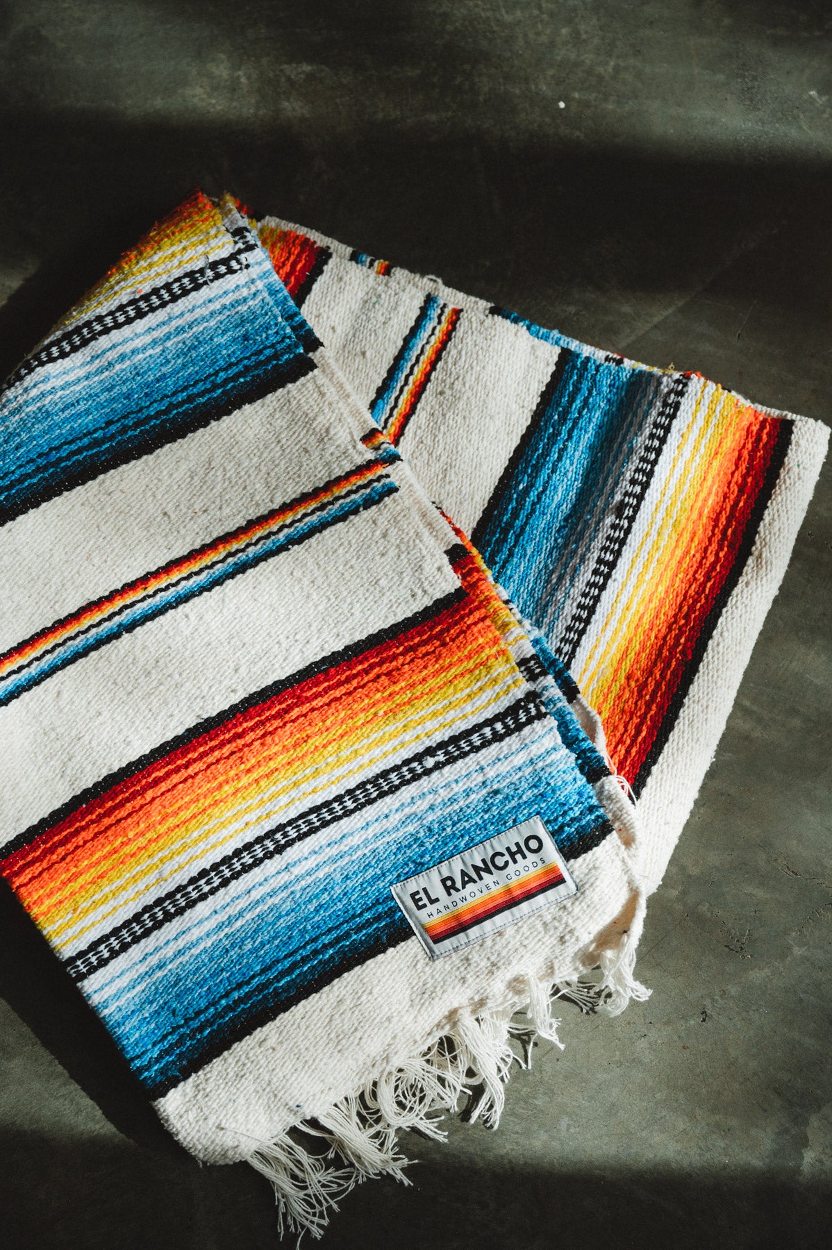Handwoven socal retro colored saltillo blanket folded on ground