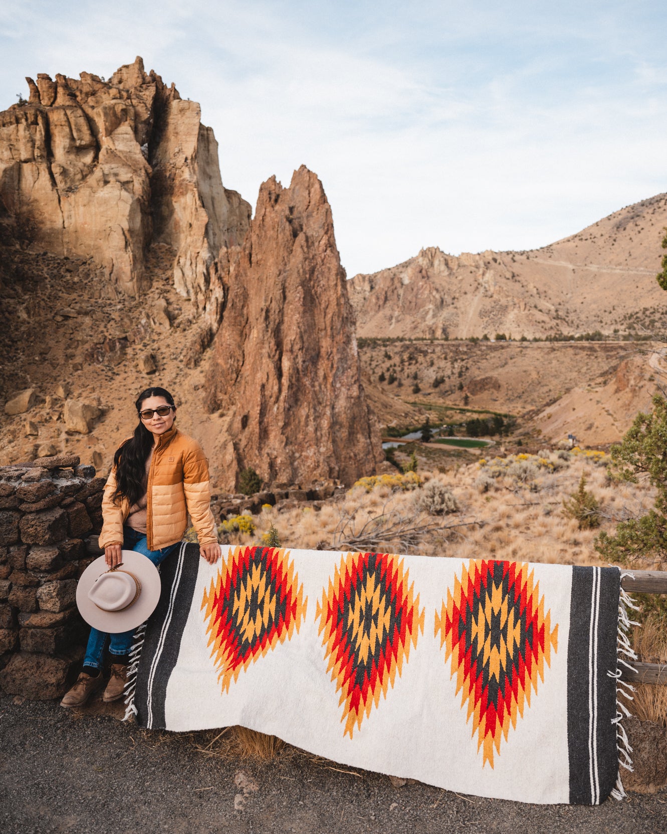 Woman standing next to southwester style diamond blanket laying over fence in the high desert