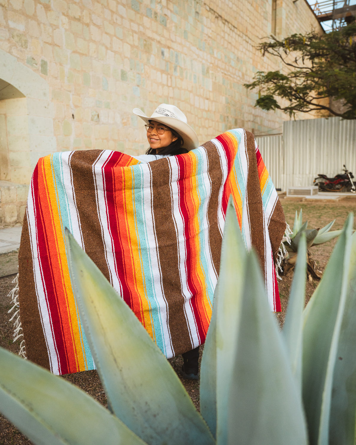 Santo Domingo Church Oaxaca and a girl standing with a handwoven mexican blanket in front of it